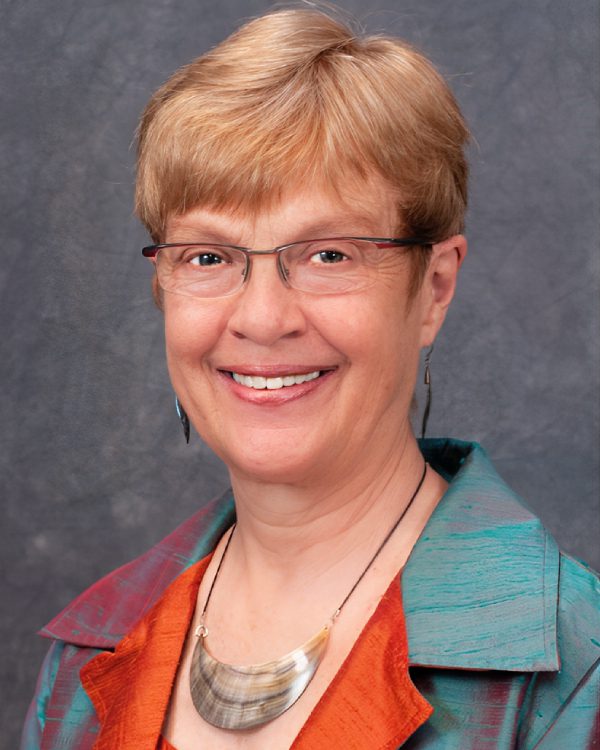 Smiling person wearing glasses and colorful jacket.