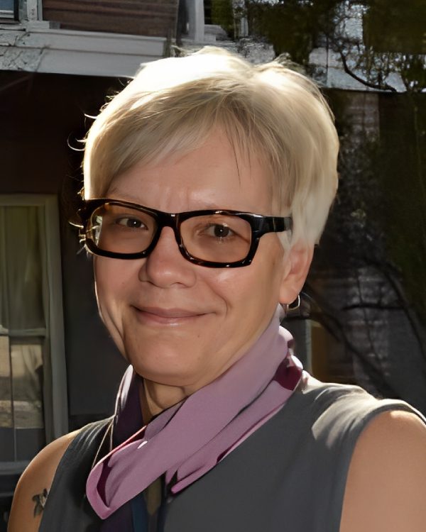 Person smiling with short hair and glasses.