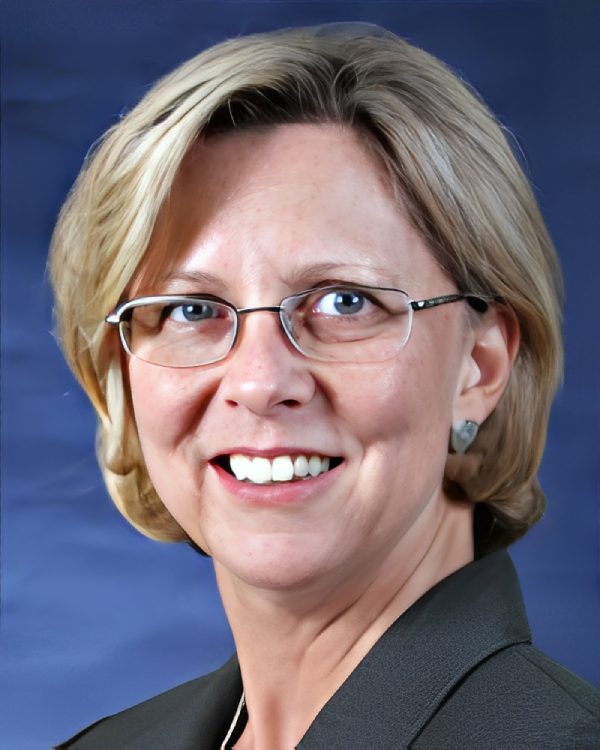 Woman smiling with glasses and short hair.