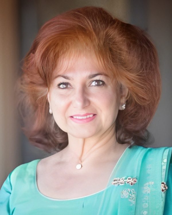 Smiling woman in turquoise dress, indoors.