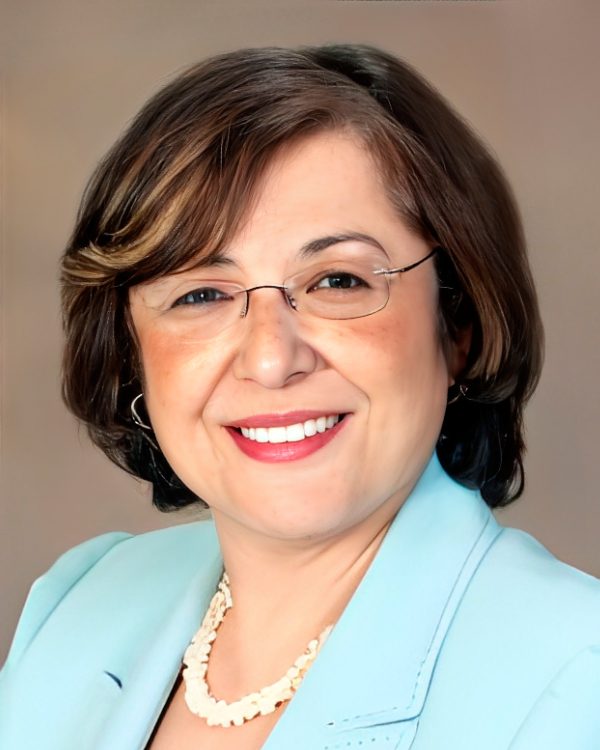 Smiling woman wearing glasses and blue blazer.