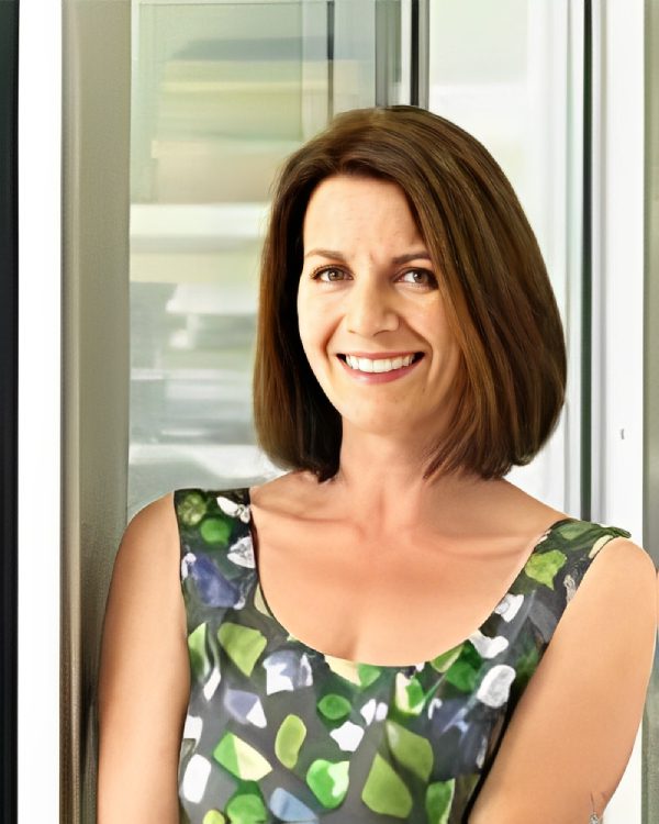 Smiling woman in patterned sleeveless dress.