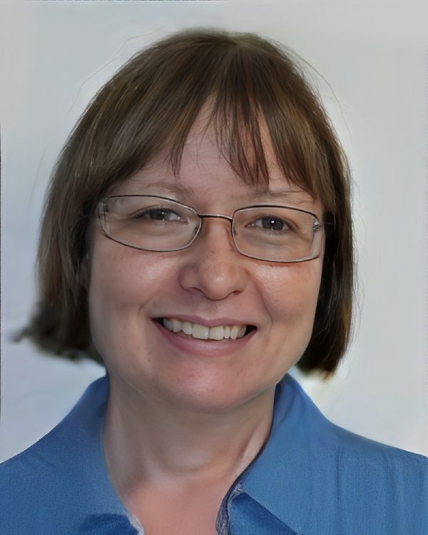 Smiling person with glasses and short hair.