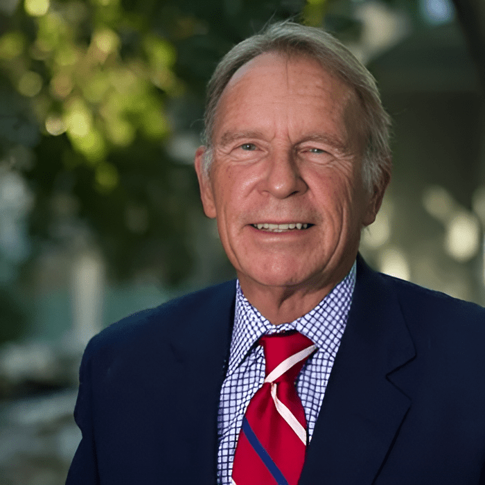 Elderly man in suit with red tie.