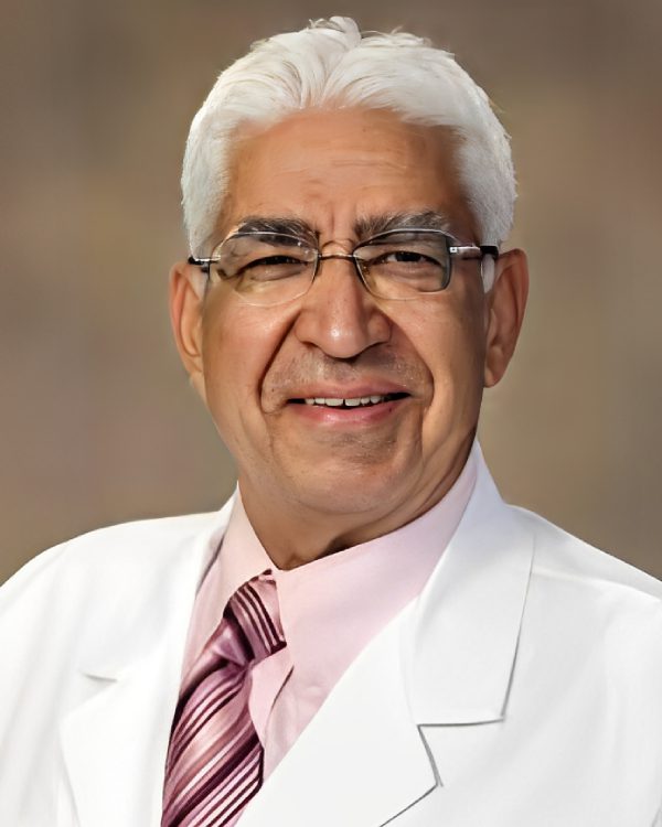 Elderly man smiling in a white coat.