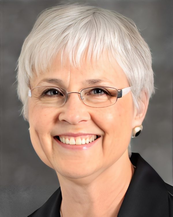 Smiling woman with short gray hair, glasses.