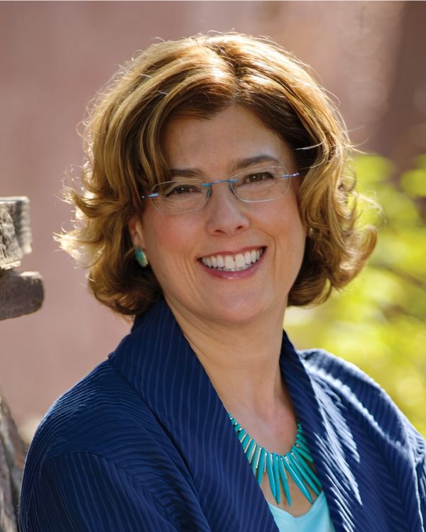 Smiling woman with glasses and curly hair.